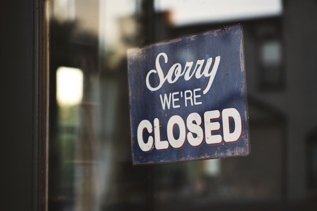 Closeup shot of a blue and white Sorry we are closed wooden signage on glass