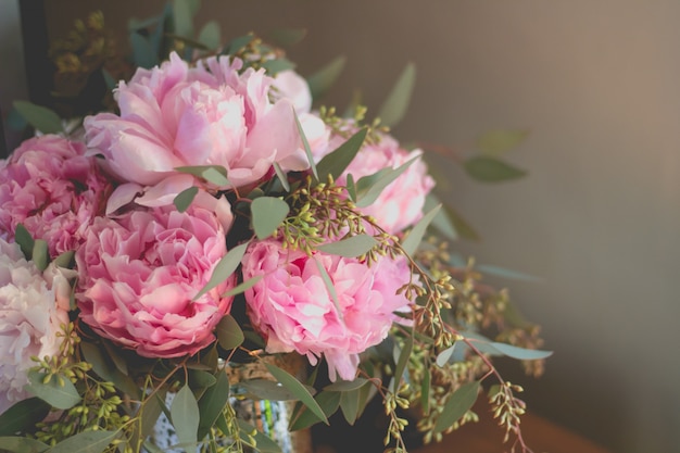 Closeup shot of a bouquet of pink roses and other flowers with green leafs