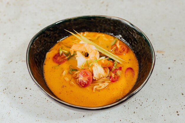 Closeup shot of a bowl of delicious Tom yum soup on a white table