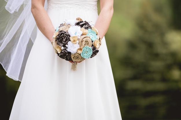 Colpo del primo piano della sposa che tiene un mazzo di fiori