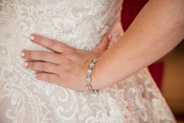 Closeup shot of the bride's wedding gown from the side, her hand put on the waist