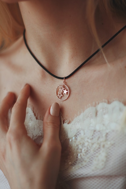 Foto gratuita colpo del primo piano di una sposa che indossa una collana pendente con un cavo nero