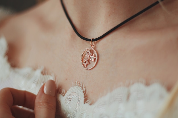 Closeup shot of a bride wearing a pendant necklace with a black cord