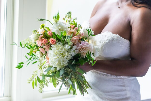 Closeup shot of a bride in a white dress holding a flower bouquet