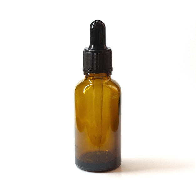 Closeup shot of a brown glass bottle and the dropper on a white space