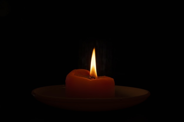 Снимок горящей свечи в темноте крупным планом