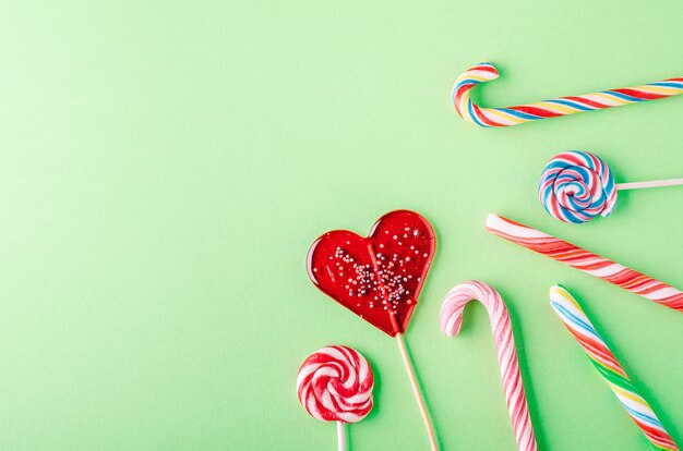 Closeup shot of candy canes and lollipops on a green background