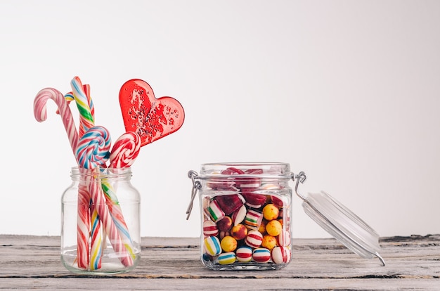 Free photo closeup shot of candy canes and other candies in glass jars on a wooden surface