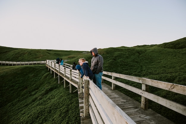 Closeup shot of a Caucasian father and boys crossing on a wooden path through mountain top