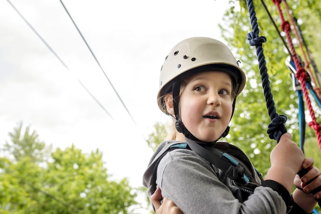 Closeup shot of caucasian female child wearing a white helmet hanging on the rope