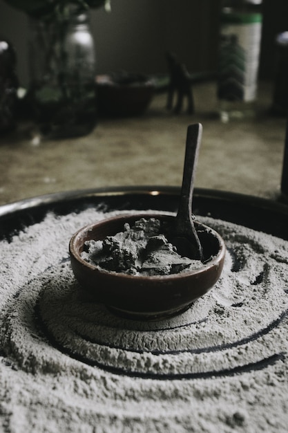 Closeup shot of a ceramic cooking pot with ingredients and a spoon in it with flour around