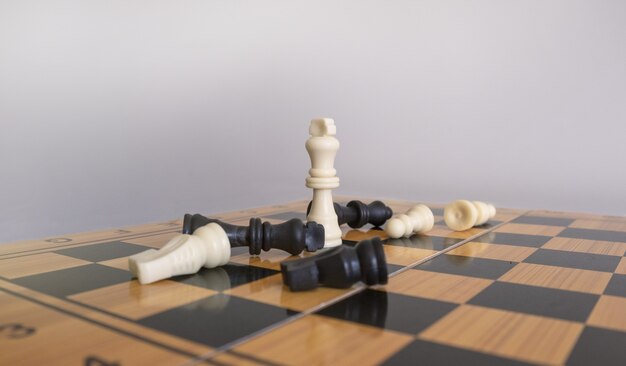 Closeup shot of chess figurines on a chessboard with a blurred white background