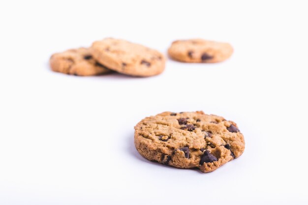 Closeup shot of a chocolate chip cookie with cookies in a blurred white background