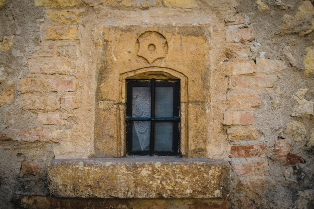 Closeup shot of a closed window on a yellow stone wall