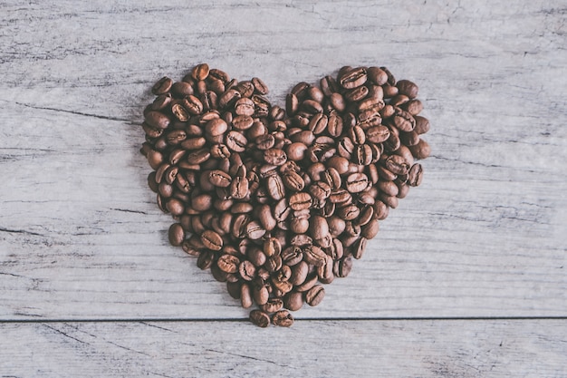 Closeup shot of coffee beans in shape of a heart on a gray wooden background