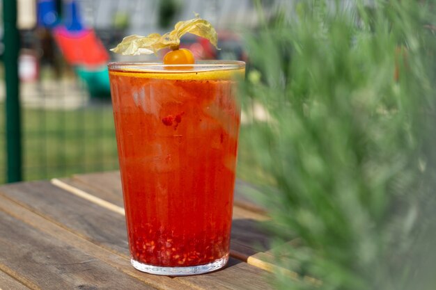 Closeup shot of a cold orange drink with herbs on a wooden surface