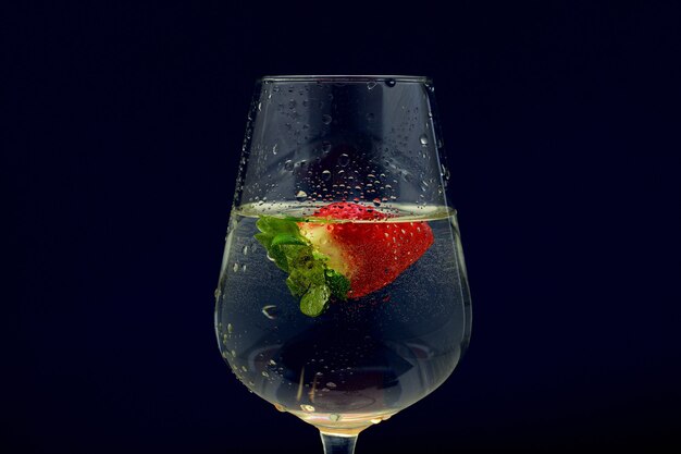 Closeup shot of a cold vine glass cocktail with a strawberry on a dark