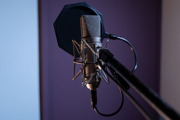 Closeup shot of a condenser microphone with a pop filter and a blurred
