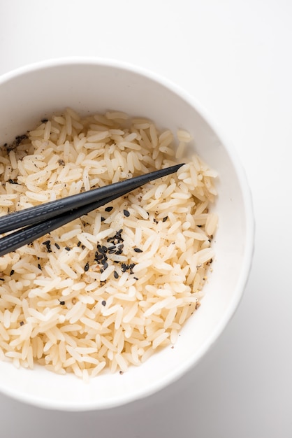 Closeup shot of cooked rice in a white plastic bowl with chopsticks