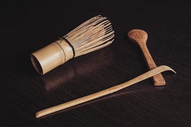 Closeup shot of a cooking brush with wooden spoons on a black background