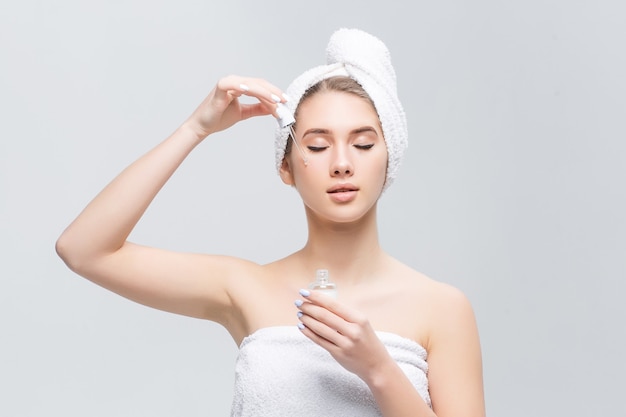 Closeup shot of cosmetic oil applying on young woman's face with pipette