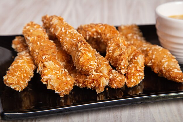 Closeup shot crispy chicken strips on a black plate