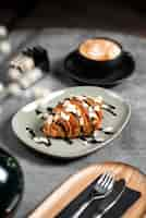 Free photo closeup shot of a croissant on a plate covered in chocolate in a cafe