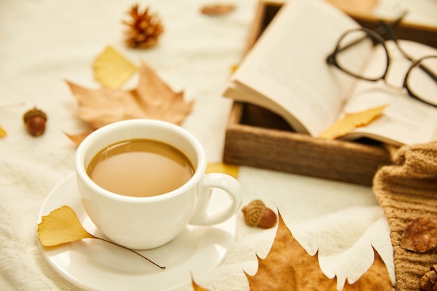 一杯のコーヒーと木の表面の紅葉のクローズアップショット