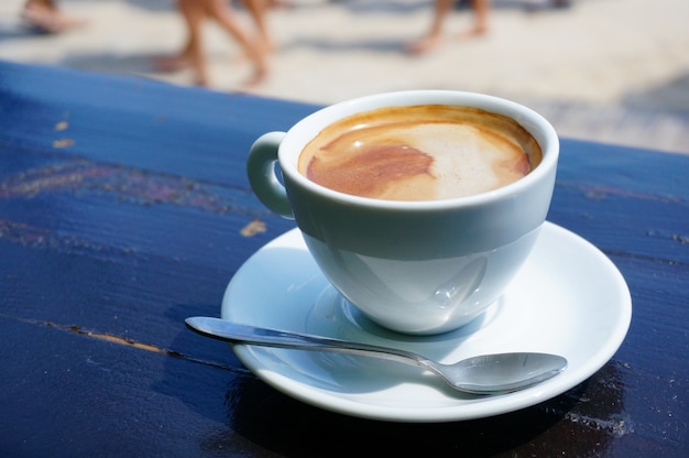 Closeup shot of a cup of coffee on a white saucer with a metal spoon