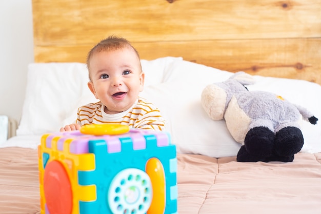 Primo piano di un bel bambino felice che gioca con un giocattolo su un letto