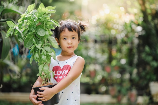 Closeup shot of a cute South Asian child holding a plant in a pa