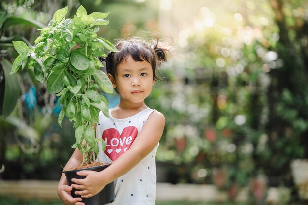 Closeup shot of a cute South Asian child holding a plant in a pa