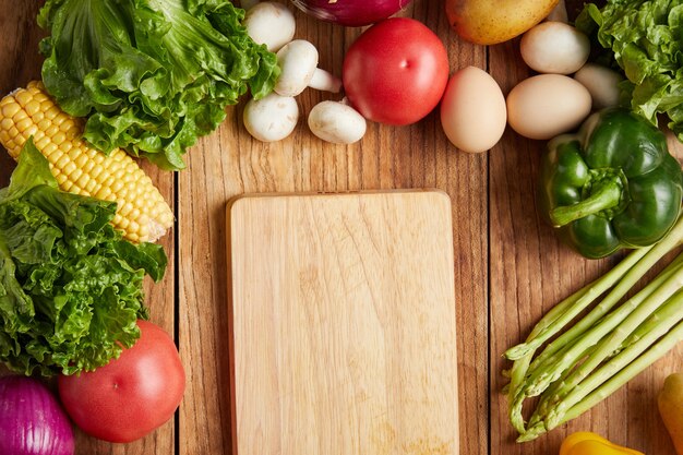 Closeup shot of cutting board and fresh vegetables on wooden surface