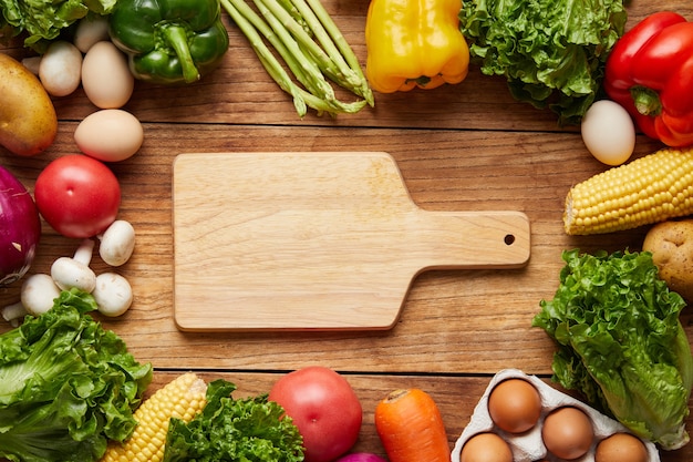 Closeup shot of cutting board and fresh vegetables on wooden