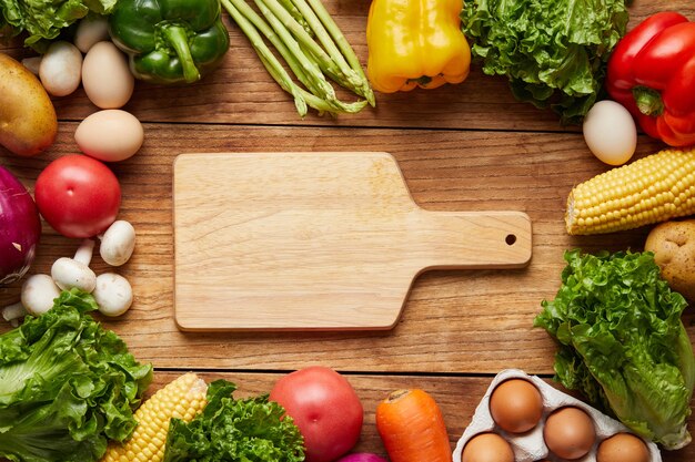 Closeup shot of cutting board and fresh vegetables on wooden