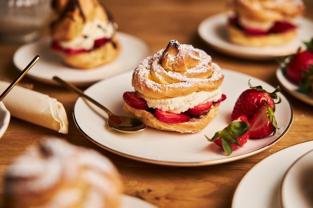 Closeup shot of delicious cream puff with strawberries on a wooden table