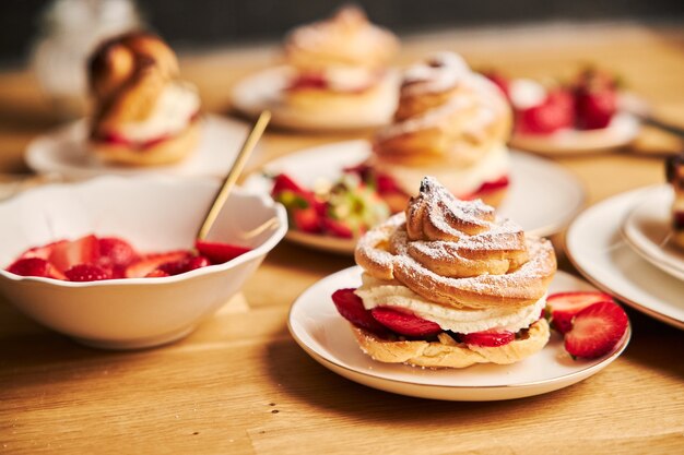 Closeup shot of delicious cream puff with strawberries on a wooden table