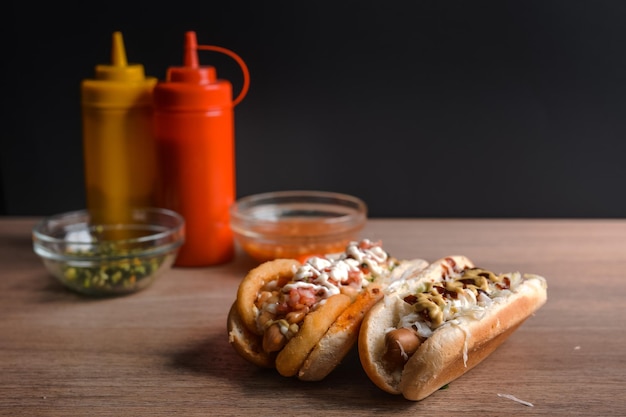 Foto gratuita scatto ravvicinato di deliziosi hot dog con gustosi condimenti con salse sullo sfondo