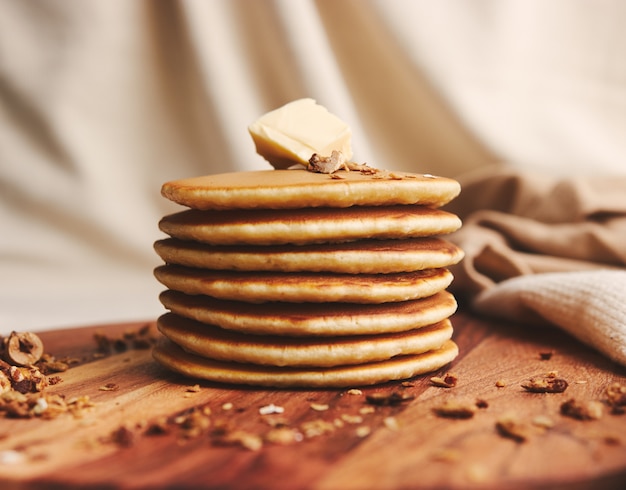 Closeup shot of delicious pancakes with butter, figs, and roasted nuts on a wooden plate