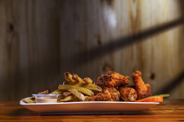 Closeup shot of delicious spiced chicken legs with french fries on the table