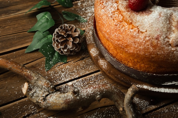 Closeup shot of a delicious sponge cake with strawberries, a pine cone, and redberries on table
