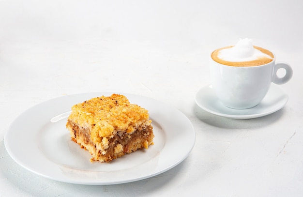 Closeup shot of a dessert plate near a cup of cappuccino isolated on white background