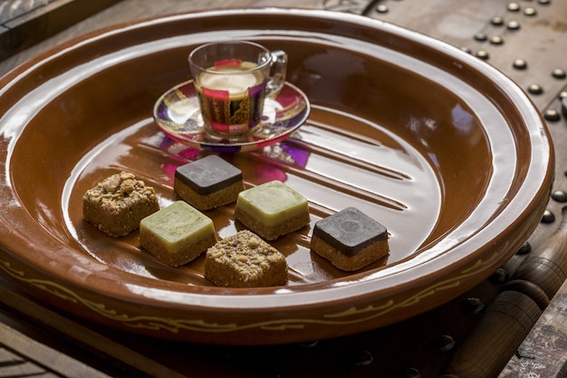 木製トレイにお茶とさまざまな種類の正方形のお菓子のクローズアップショット