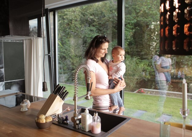 窓の外を見ている彼女の赤ちゃんとヨーロッパの女性のクローズアップショット