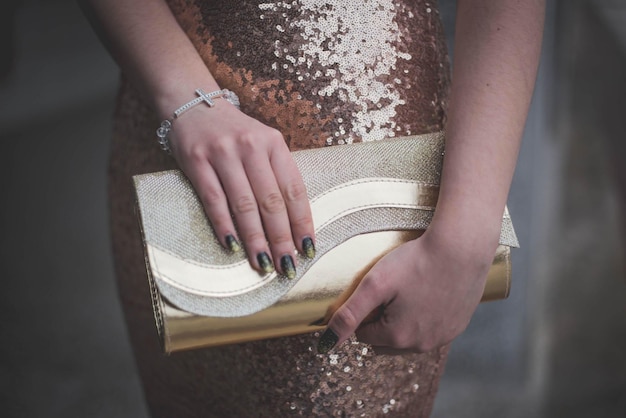 Closeup shot of a fashionable female in a fancy evening dress holding a clatch bag