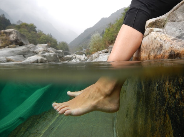 Free photo closeup shot of feet underwater in a river with mountains in ticino, switzerland.