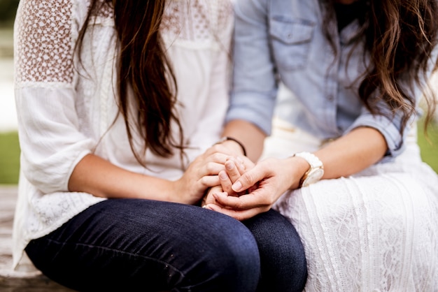 Closeup shot of female couples holding hands with a blurred background