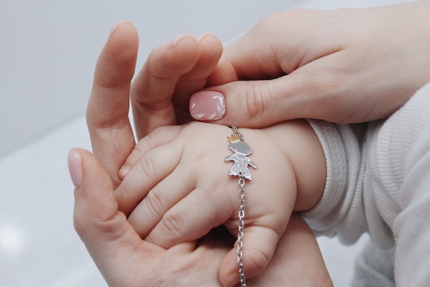 Closeup shot of a female putting a cute bracelet on her baby's hand