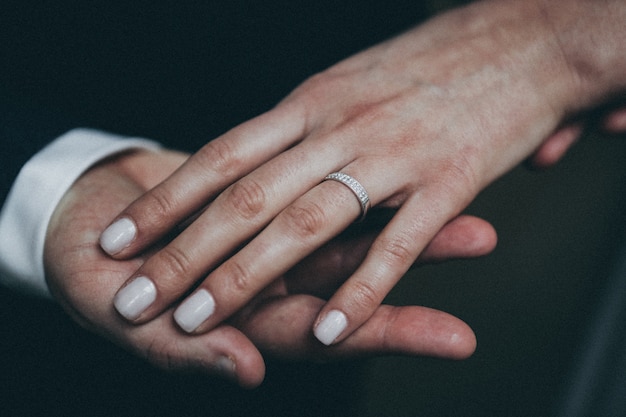 Closeup shot of a female's hand with silver ring on a male's hand with a blurred background