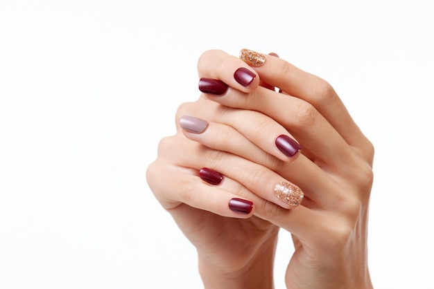 Closeup shot of a female's hands with beautiful nail polish on a white background